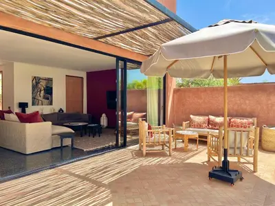 a patio with an umbrella and a living room at Villa Bohō - 4 suites in El Rhechat