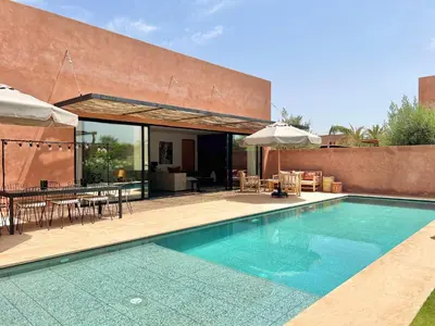 a swimming pool with a table and chairs and an umbrella at Villa Bohō - 4 suites in El Rhechat