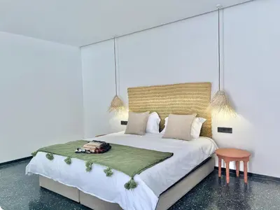 a bedroom with a large bed and a chair at Villa Bohō - 4 suites in El Rhechat