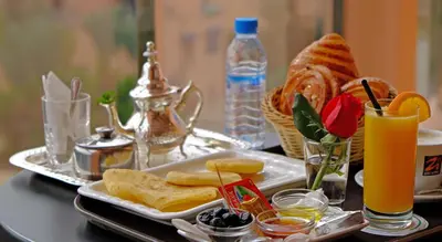 a table with a plate of food and a glass of orange juice at Appart Hôtel Mouna in Marrakech