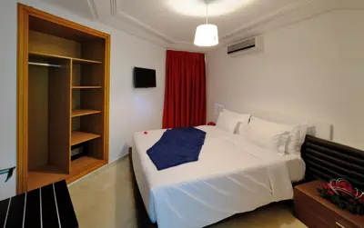 a bedroom with a white bed and a red curtain at Appart Hôtel Mouna in Marrakech