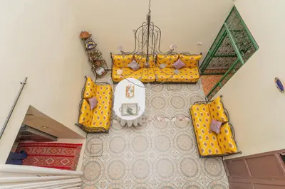 a room with yellow furniture and a chandelier at Dar Si Ahmed in Marrakech