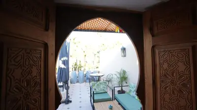 an arched doorway into a room with a table and chairs at Riad Oumhani in Marrakech