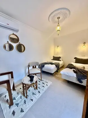 a bedroom with two beds and a table in it at Riad Oumhani in Marrakech