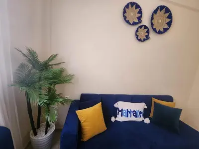 a blue couch with yellow pillows and a clock at Aéroport appartement Marrakech in Marrakech