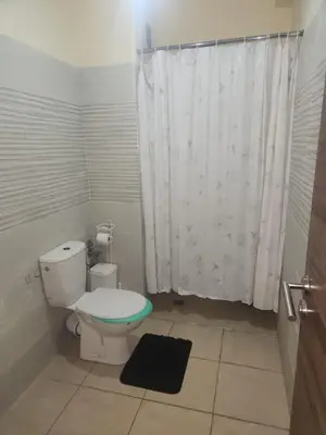 a bathroom with a toilet and a white shower curtain at Aéroport appartement Marrakech in Marrakech