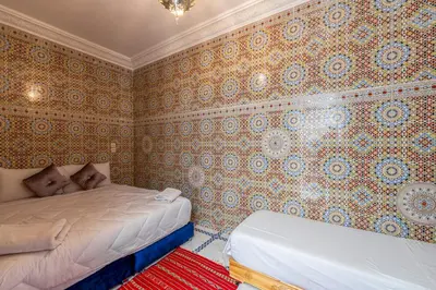 a bedroom with two beds in a room with wallpaper at Dar N3 in Marrakech