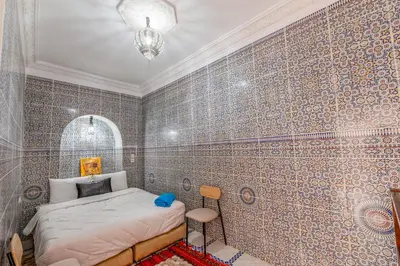 a bedroom with a bed and a tiled wall at Dar N3 in Marrakech