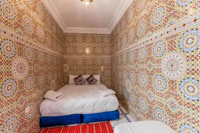 a small bedroom with a bed in a room with wallpaper at Dar N3 in Marrakech