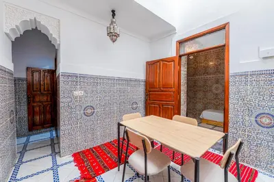 a table and chairs in a room with blue and white tiles at Dar N3 in Marrakech