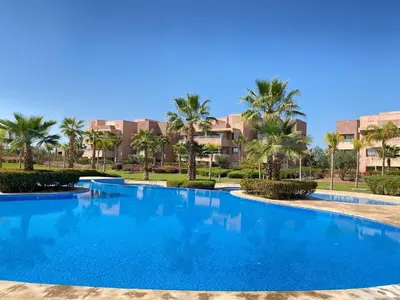 a swimming pool in a resort with palm trees at Golf Prestigia Marrakech in Marrakech