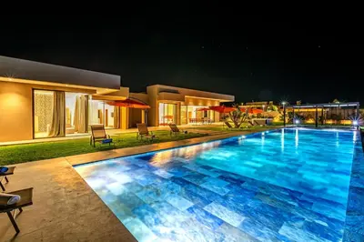 a swimming pool in front of a house at night at Chic Villa Jacuzzi and Green Space in Marrakech