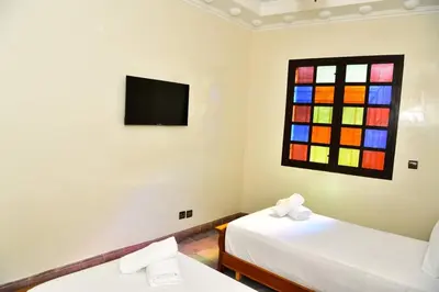 a room with two beds and a stained glass window at Marrakech Centre Guéliz – Calme & authentique in Marrakech