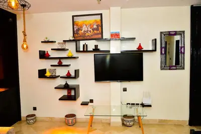 a living room with a tv on a wall with shelves at Marrakech Centre Guéliz – Calme & authentique in Marrakech
