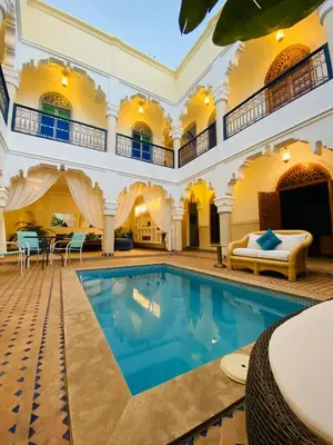an indoor swimming pool in a building with a large house at Riad El Laadel Marrakech in Marrakech