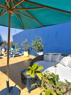 a patio with a bed and an umbrella at Riad El Laadel Marrakech in Marrakech
