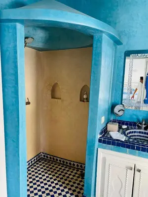 a blue bathroom with a black and white tiled floor at Riad El Laadel Marrakech in Marrakech