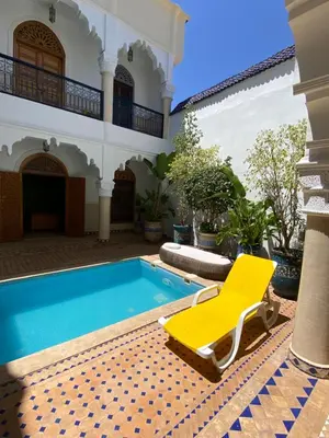 a pool with a yellow chair and a house at Riad El Laadel Marrakech in Marrakech