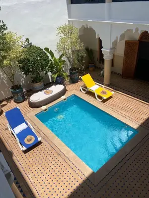 a swimming pool on a patio with a chair and a chaise lounge at Riad El Laadel Marrakech in Marrakech