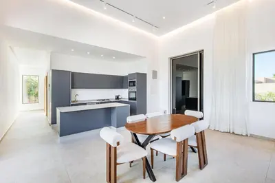 a kitchen with a wooden table and white chairs at Luxury Villa with No Overlooking 15 min from Marrakech in Marrakech