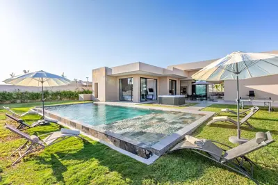 a house with a swimming pool and two umbrellas at Villa Magique Piscine Chauffée Et Jacuzzi in Marrakech