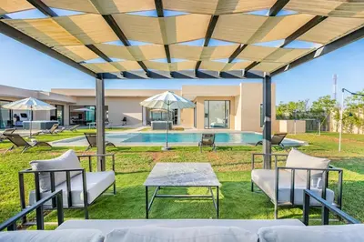 a patio with a table and chairs and a pool at Villa Magique Piscine Chauffée Et Jacuzzi in Marrakech