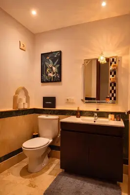 a bathroom with a toilet and a sink and a mirror at Luxe Hivernage Piscine Géante & Terrasse XXL in Marrakech