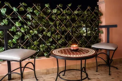 a table and two stools in front of a green wall at Central location in Gueliz in Marrakech