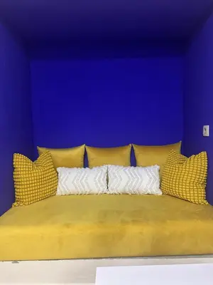 a bed with yellow pillows and a blue wall at Blue and sun Majorelle comfort and spacious in Marrakech