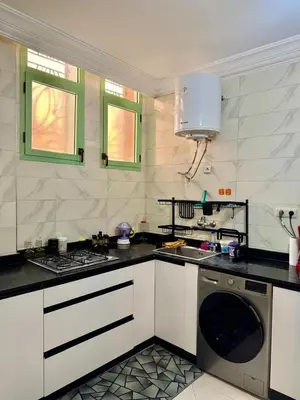 a kitchen with white cabinets and a dishwasher at Gouarial in Marrakech
