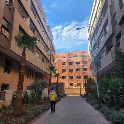 a person walking down a street between buildings at New comfy appartement-centre -Menara-Gueliz-aero in Marrakech