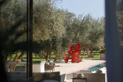 a pool with a red sculpture next to trees at Elegant 3-BR Villa with breakfast included in Marrakech