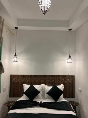 a bedroom with a bed with black and white pillows at Riad Lalla Nadia in Marrakech
