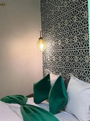 a bedroom with a bed with green and white pillows at Riad Lalla Nadia in Marrakech