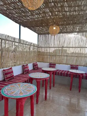 a room with red tables and benches and windows at Riad Lalla Nadia in Marrakech
