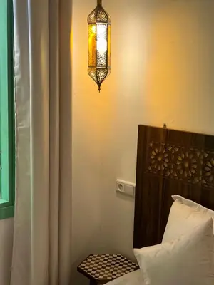 a room with a bed and a light on the wall at Riad Lalla Nadia in Marrakech