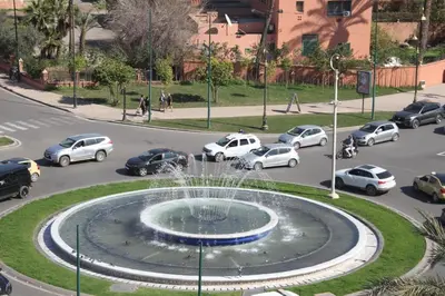 a fountain in the middle of a street with cars at Appartement plein centre marrakech p in Marrakech