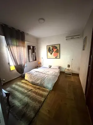 a bedroom with a large bed and a wooden floor at Appartement plein centre marrakech p in Marrakech