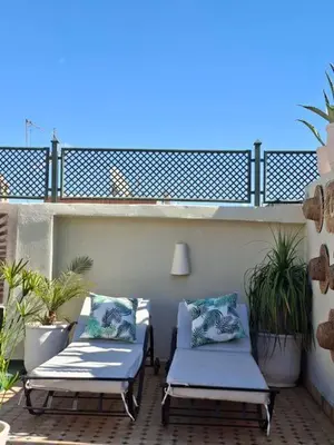 a patio with two chaises and plants on a balcony at Riad Millefeuilles in Marrakech