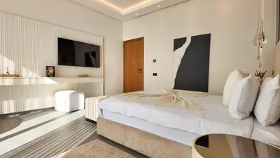 a white bedroom with a bed and a table at Villa Janna heated pool without overlooking in Marrakech