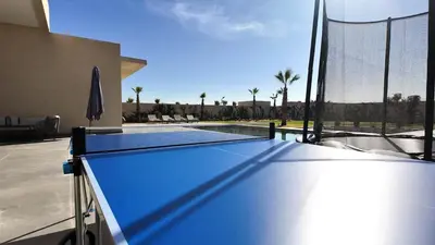 a ping pong table in front of a swimming pool at Villa Janna heated pool without overlooking in Marrakech