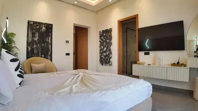 a bedroom with a large bed with a television on the wall at Villa Janna heated pool without overlooking in Marrakech