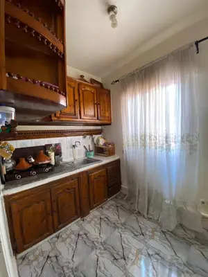 a kitchen with wooden cabinets and a window at Apartment near train station Marrakesh in Marrakech