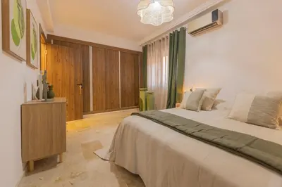 a bedroom with a large bed and a chandelier at Sublime 3-bedroom duplex with pool in Marrakech