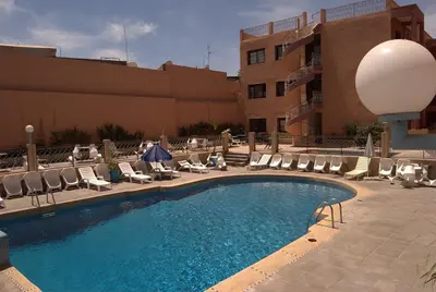 a swimming pool with lounge chairs and a building at GRAND HOTEL TAZi in Marrakech