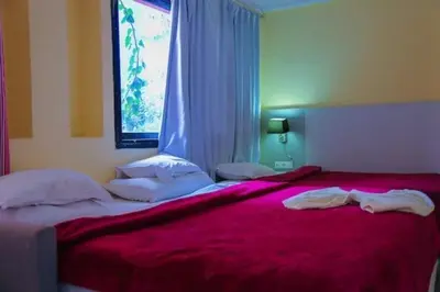 a bedroom with two beds with red sheets and a window at GRAND HOTEL TAZi in Marrakech