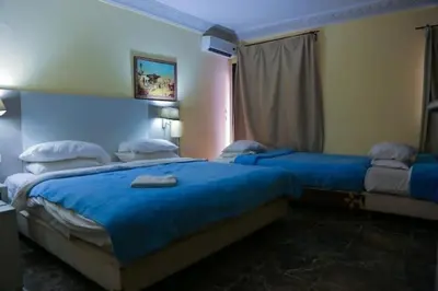 a bedroom with two beds with blue sheets and a window at GRAND HOTEL TAZi in Marrakech