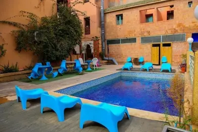 a swimming pool with blue chairs next to a building at GRAND HOTEL TAZi in Marrakech