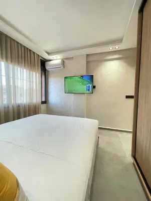 a bedroom with a white bed and a flat screen tv at Comfort Suites Marrakech in Marrakech