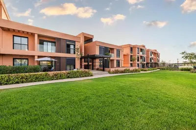 an exterior view of an apartment complex with a green lawn at Noria Modern & Cozy Piscine in Marrakech
